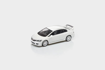 A white die-cast model car, resembling a Honda Civic, shown from a three-quarters front angle on a light gray reflective studio background.