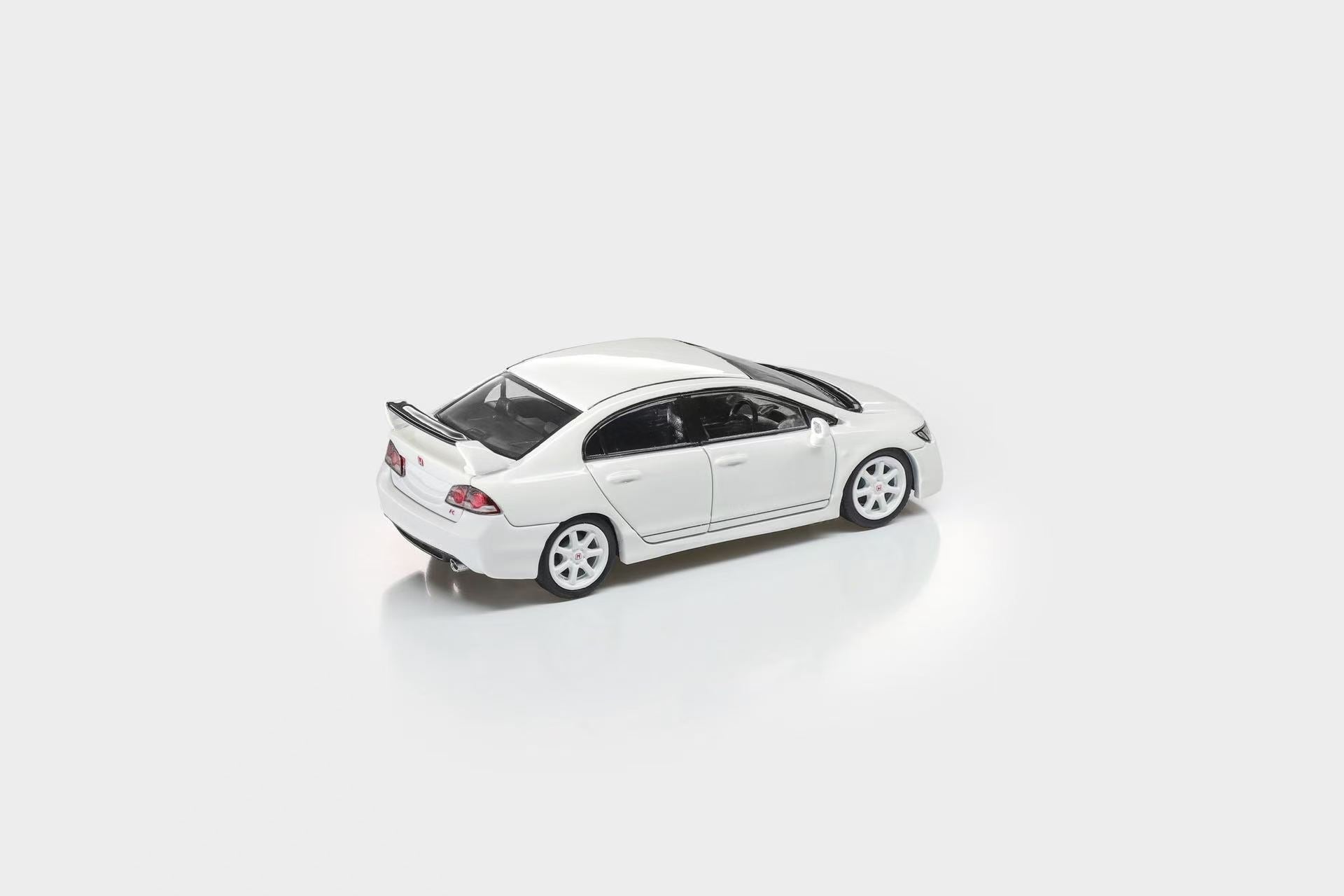 A white diecast model of a Honda Civic sedan with a rear spoiler, shown from a three-quarters rear angle on a clean white background.