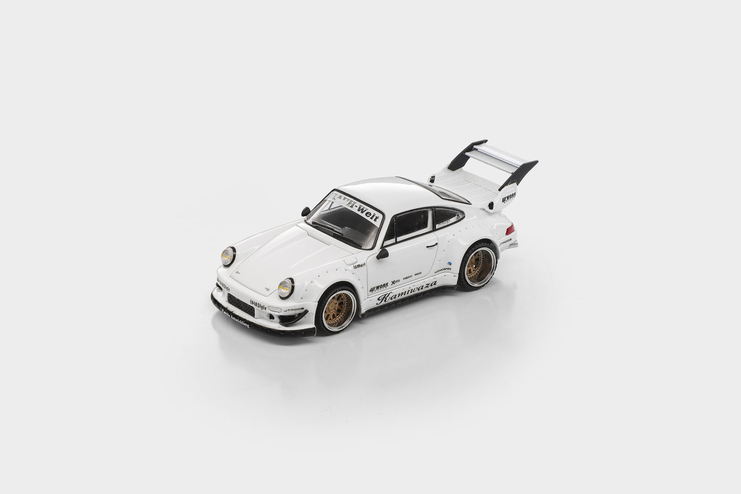 A white die-cast model car with gold wheels and a black rear spoiler, photographed on a clean light gray background.