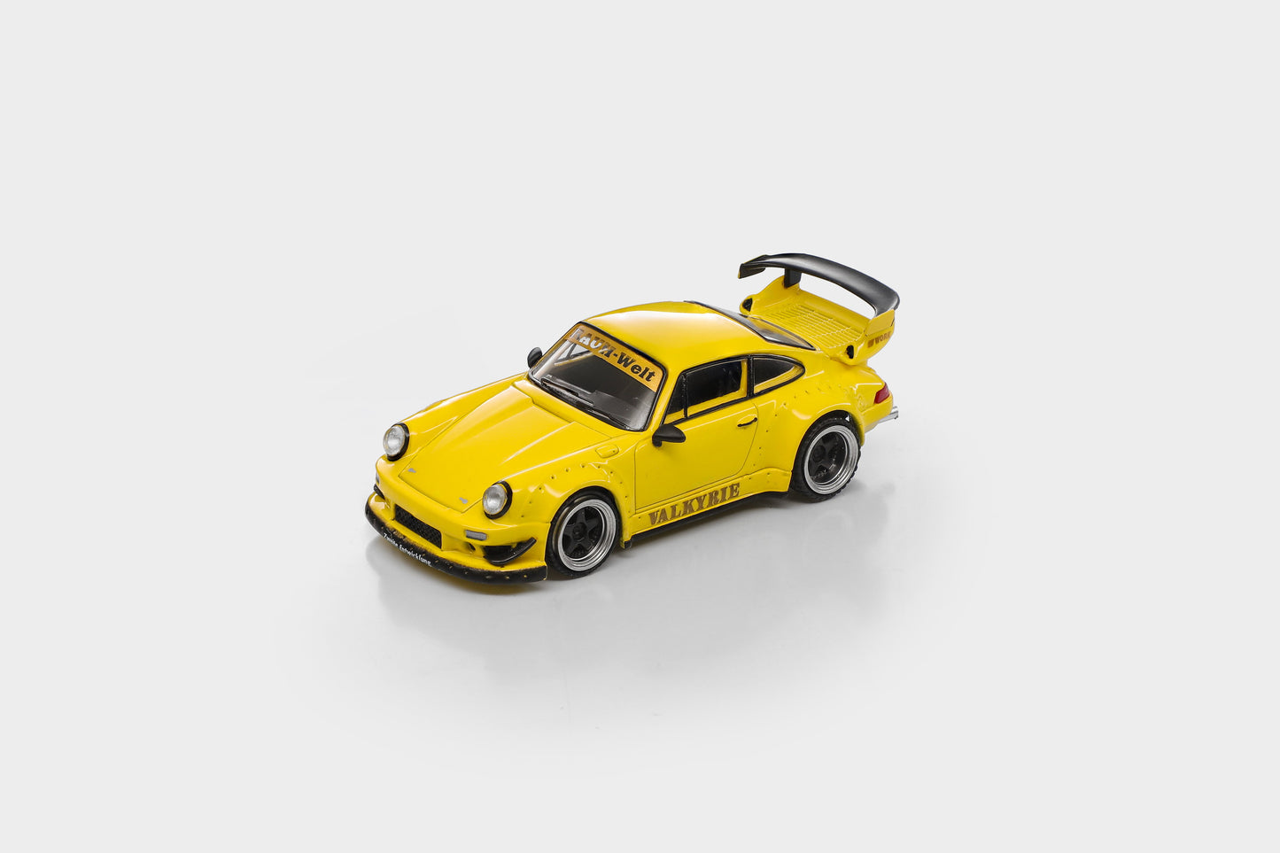 A yellow model car with black and gray accents, featuring 'VALKYRIE' printed on the side, shown on a light gray background.