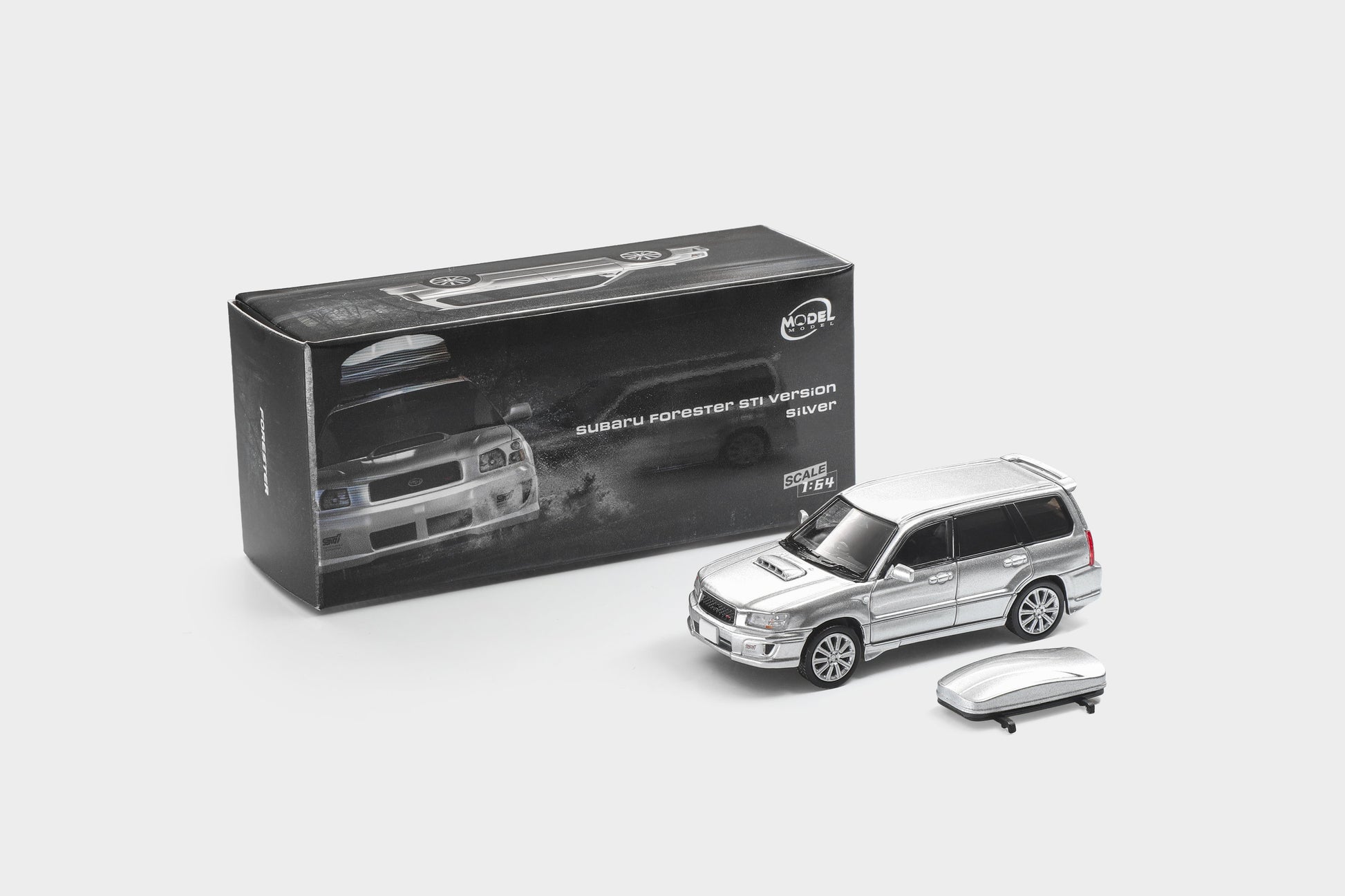 A silver diecast model of a Subaru Outback Stonewall SUV shown next to its black retail packaging box and a matching silver roof rack accessory, on a light gray background.
