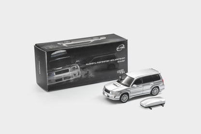A silver diecast model of a Subaru Outback Stonewall SUV shown next to its black retail packaging box and a matching silver roof rack accessory, on a light gray background.