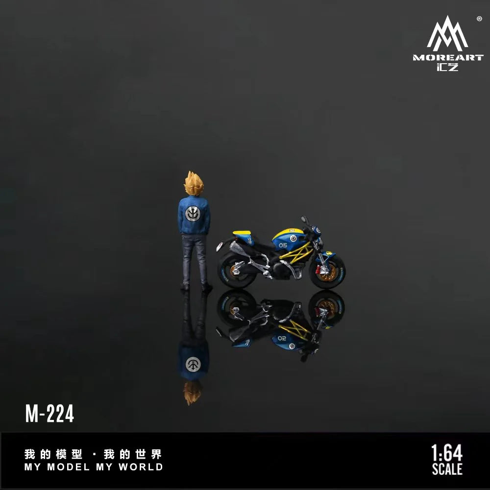 A 1:64 scale model figurine of a blonde character in a blue jacket standing next to a blue and yellow motorcycle, shown on a dark reflective surface with its reflection visible. The brand logo 'MOREART E-Z' is in the top right, and product text 'M-224' and '1:64 SCALE' is in the bottom.