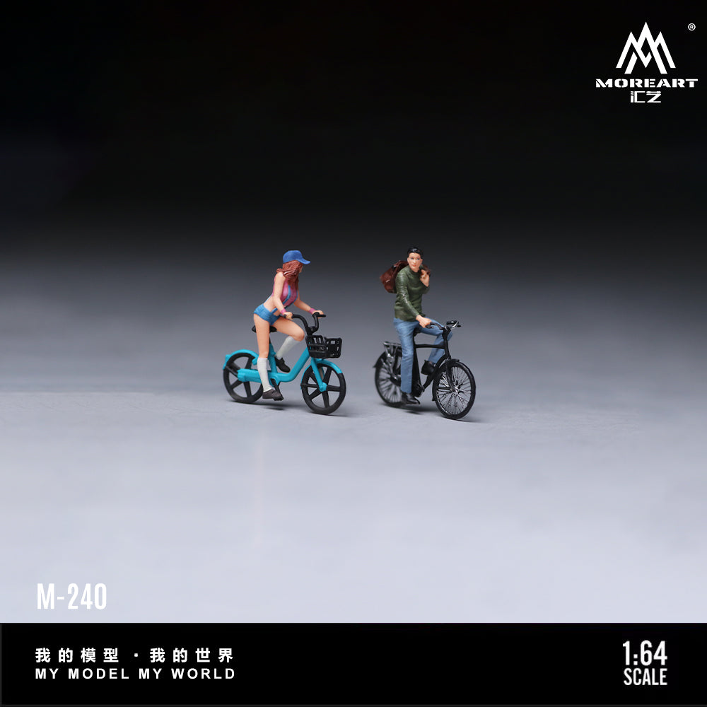 MoreArt 1:64 Cycling Couple Figure Set M-240 displayed in a clean studio scene featuring two miniature cyclist figures with detailed bicycles, perfect for 1:64 scale diecast model car dioramas, city layouts and miniature collections.