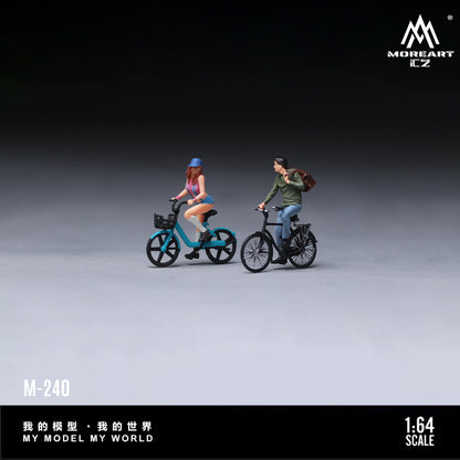 MoreArt 1:64 Cycling Couple Figure Set M-240 shown in a studio side view featuring two miniature cyclist figures riding detailed bicycles, ideal for 1:64 scale diecast model car dioramas, city street scenes and miniature displays.