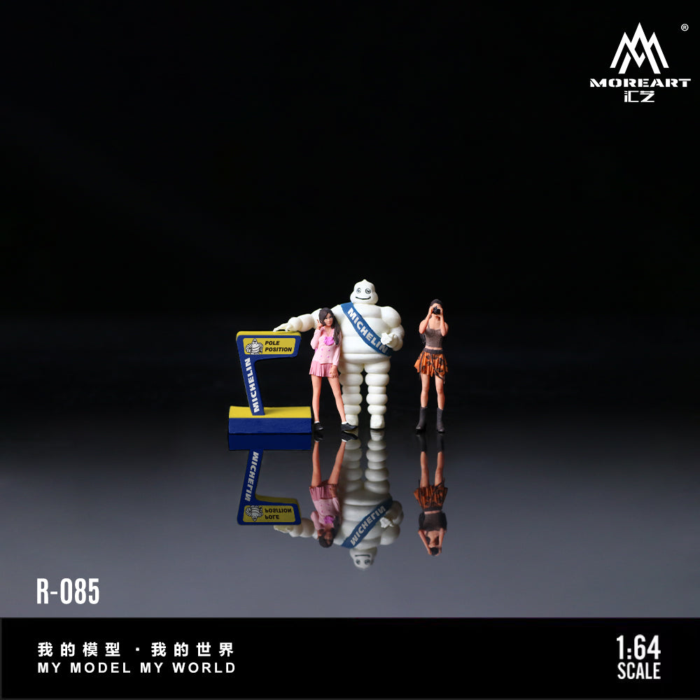 A collectible miniature figurine set from MOREART, featuring a white tire character wearing a blue sash alongside two small female figures, displayed on a reflective black surface with product text overlays.