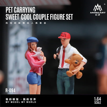 Two figurines of a couple holding pets with 'MoreArt' branding.