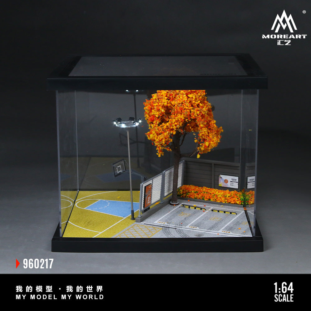 Model basketball court with trees and lights in a clear display case, featuring the MoreArt logo.