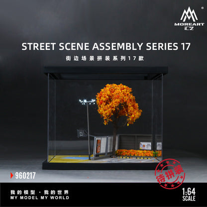 A 1:64 scale street scene assembly model set by MOREART, featuring a miniature basketball court with a bright orange tree, a light pole, and a small building, shown inside a clear display case against a dark background.