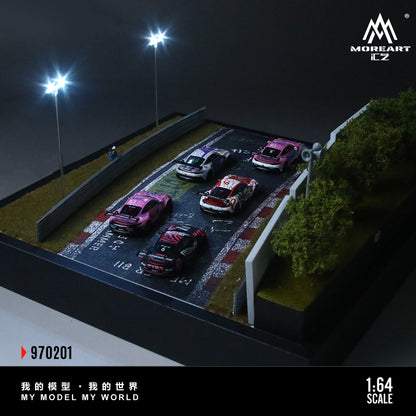 Model cars on a miniature racetrack with 'MoreArt CZ' branding.