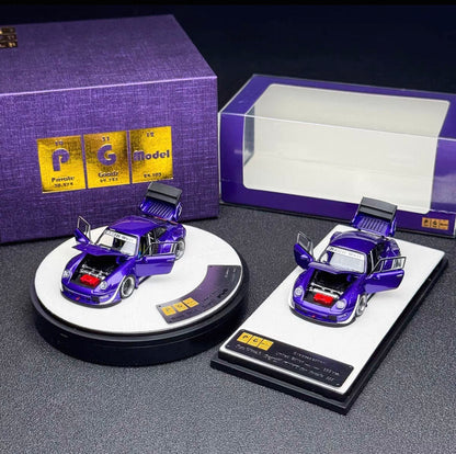 Two miniature purple model cars displayed on round and rectangular stands, with a purple branded box and a clear display box in the background.