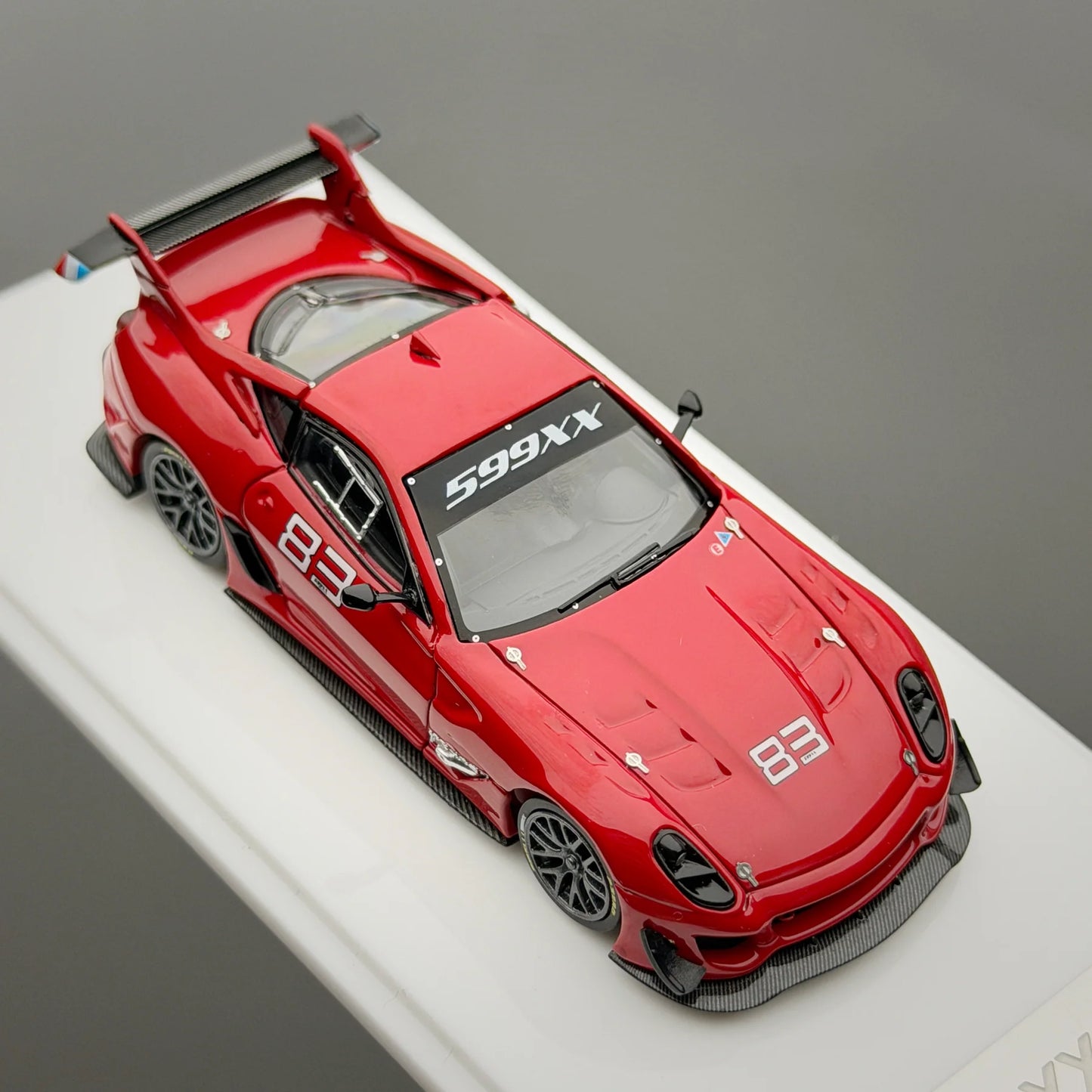 Red sports car model with '599XX' and '83' branding on a gray background