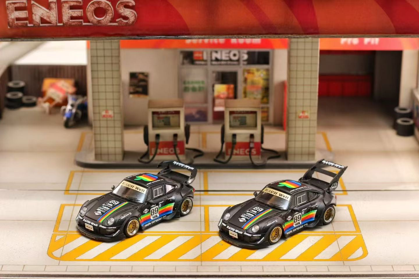 Two Street Weapon RWB 993 with Apply livery on a scale model gas station with 'ENEOS' branding.