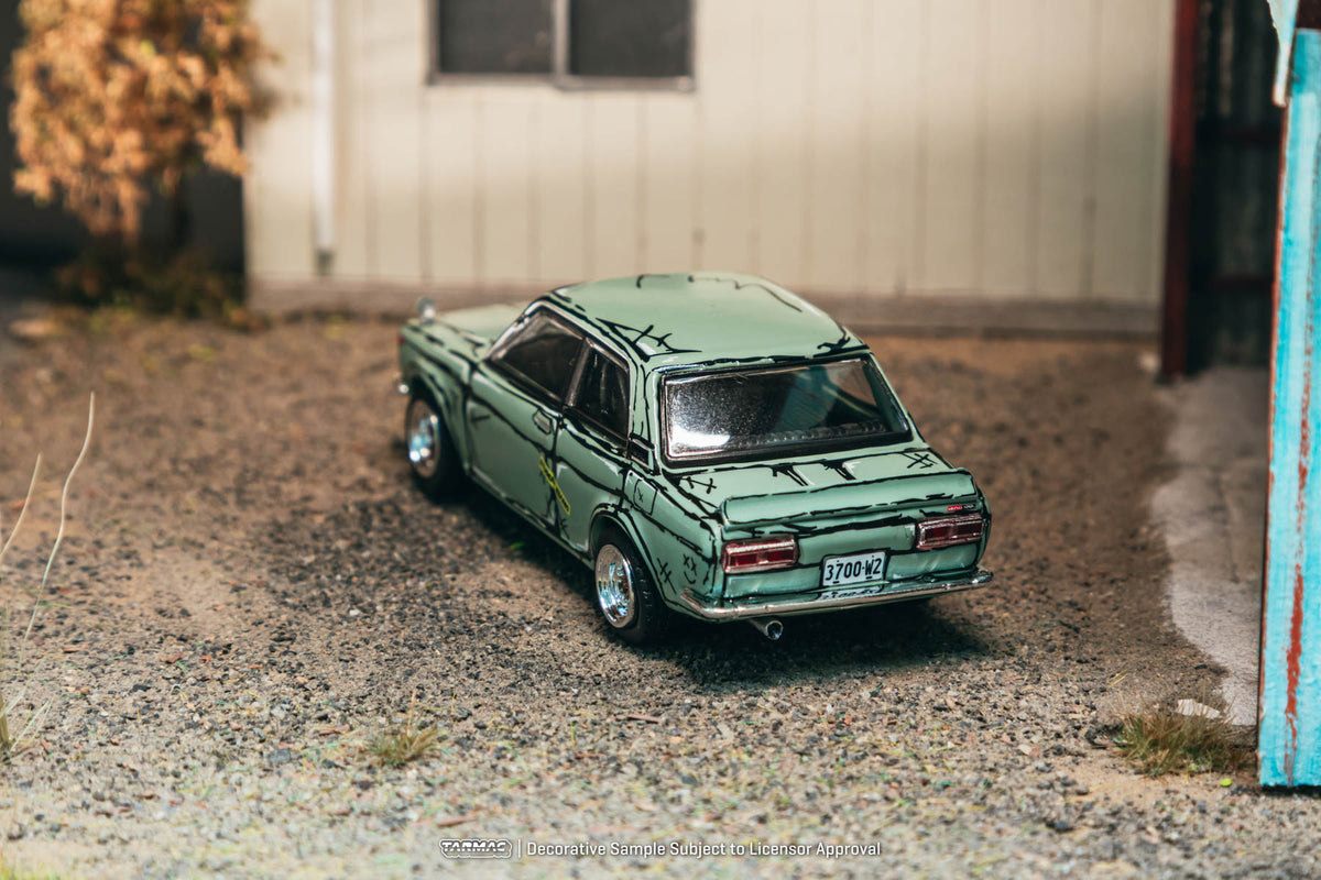 Tarmac Works 1:64 Datsun Bluebird SSS 510 Formosa weathered diecast model with patina finish in garage diorama
