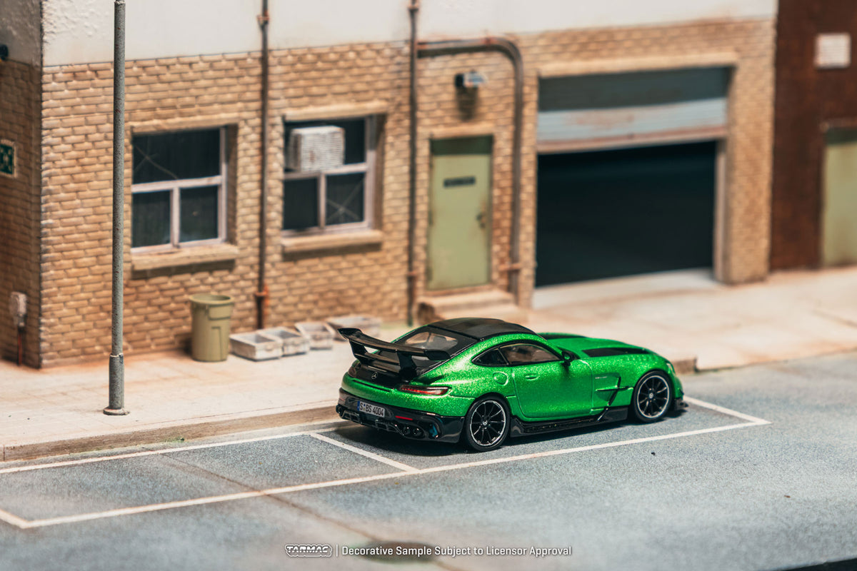 Green sports car on a model street with a brick building in the background