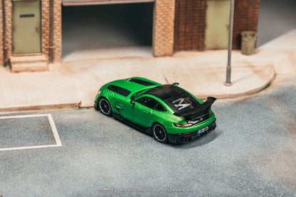 Green sports car model on a miniature street with buildings in the background