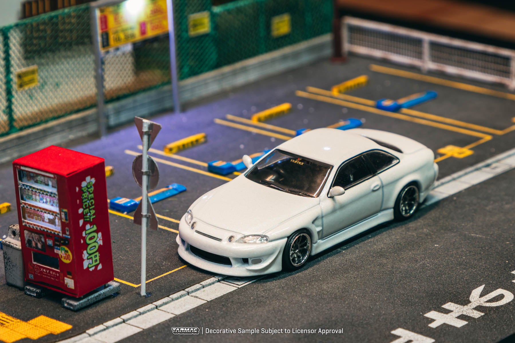 Model car on a miniature street with a red vending machine and traffic lights.
