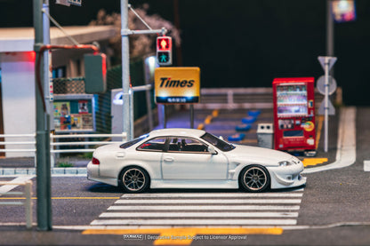 Model car on a miniature street with traffic lights and signs at night.