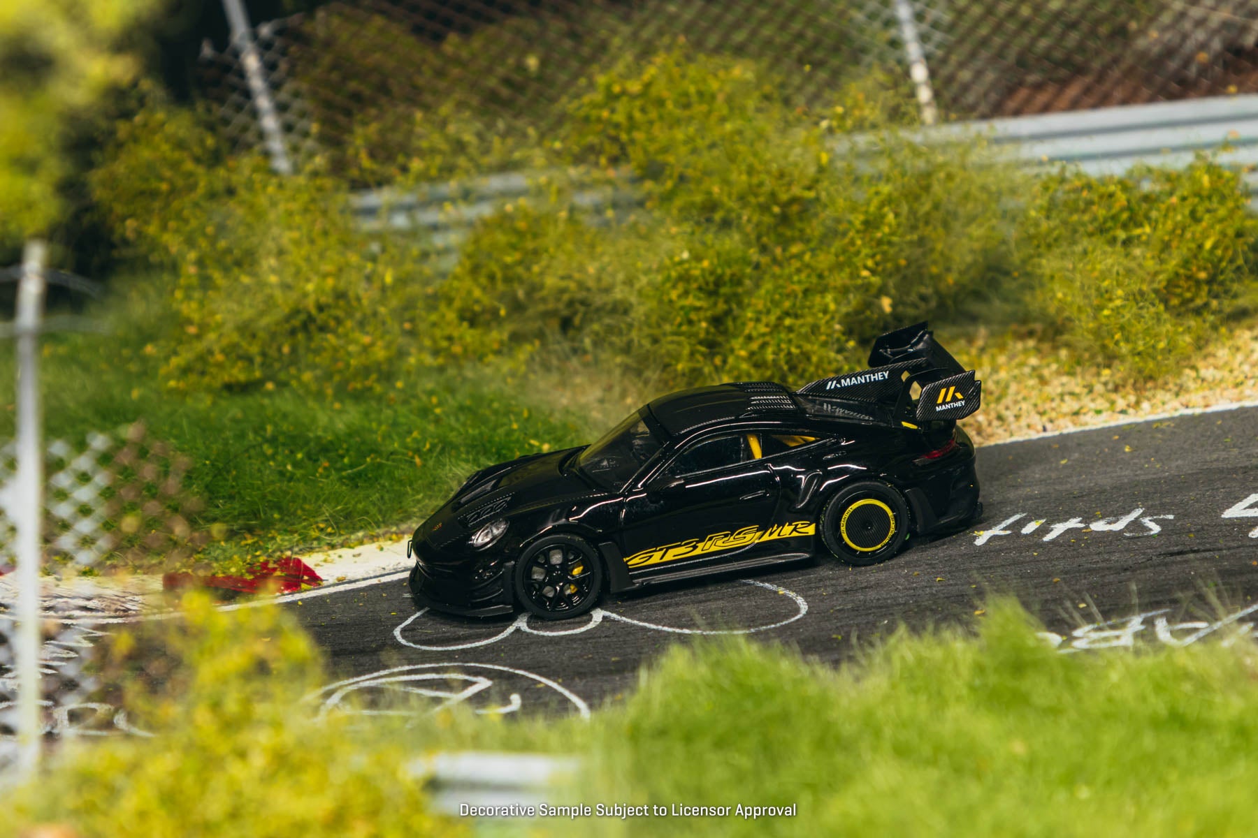 Model car on a miniature race track with greenery in the background