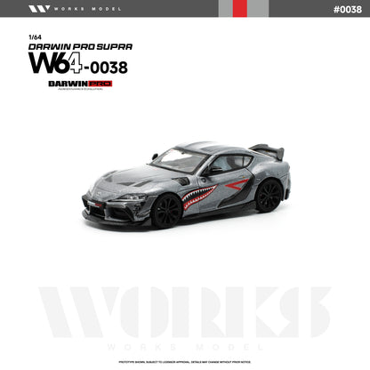 Front three-quarter view of the Works Model 1:64 Toyota GR Supra DarwinPRO in metallic gray with shark mouth graphics, black wheels, carbon-style aero kit, vented hood, and rear wing. Product code W64-0038. Prototype diecast model on a white background.