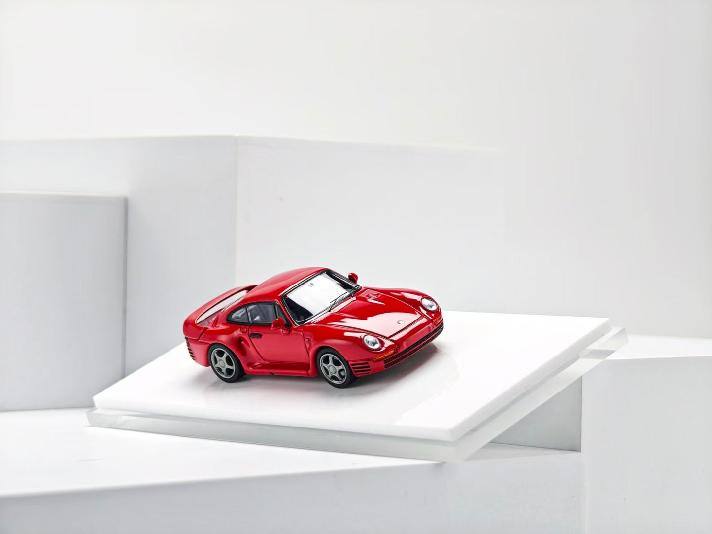 Red sports car model on a white platform with a white background