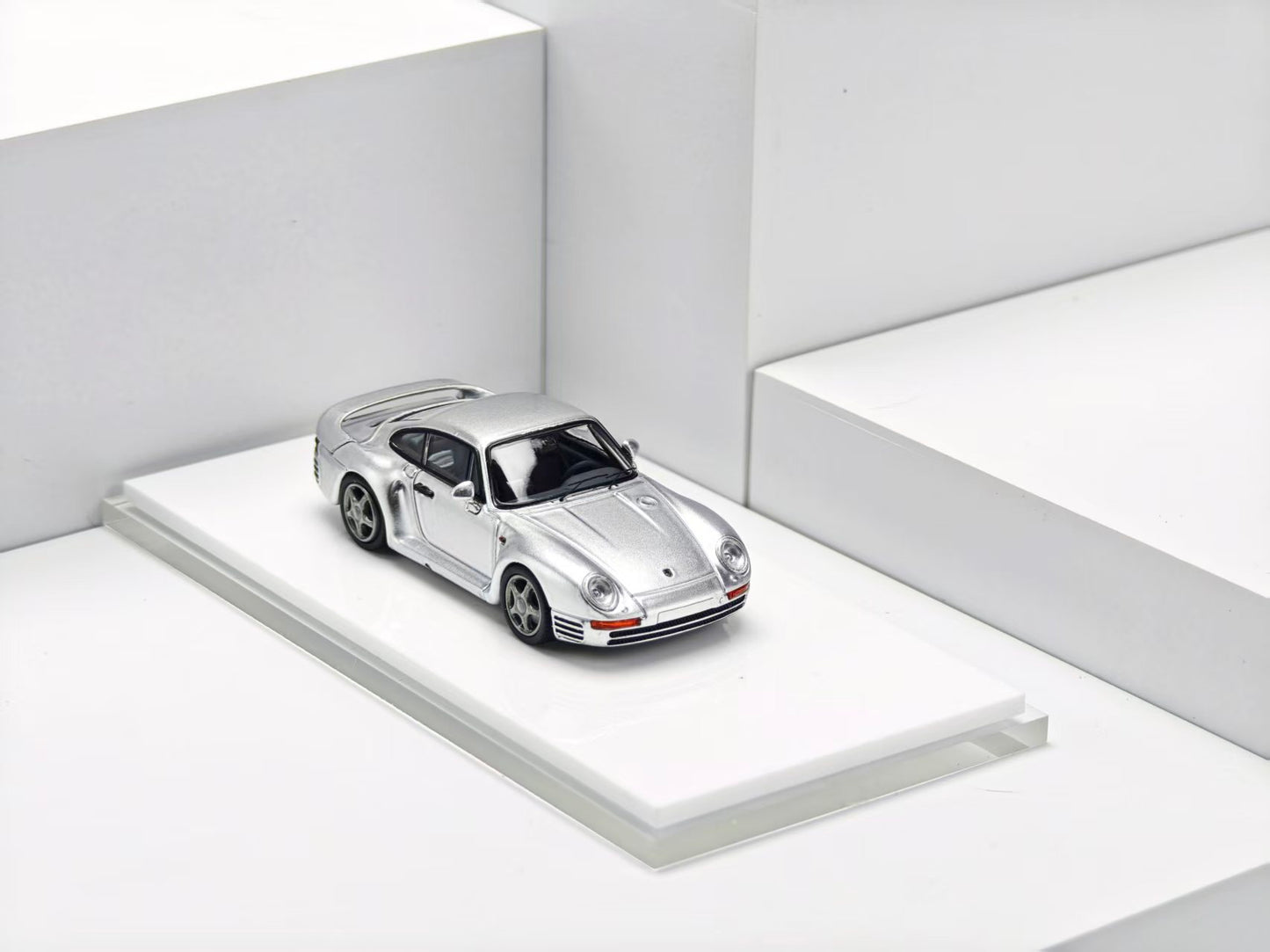 Silver sports car model on a white platform with a white background