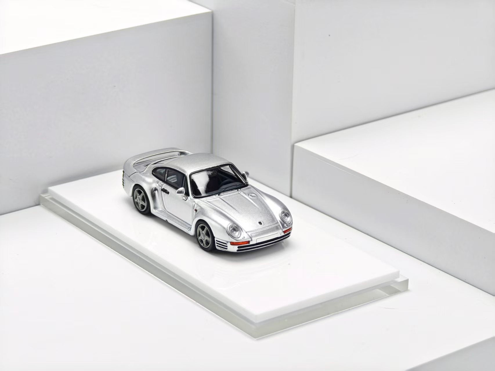 Silver sports car model on a white platform with a white background