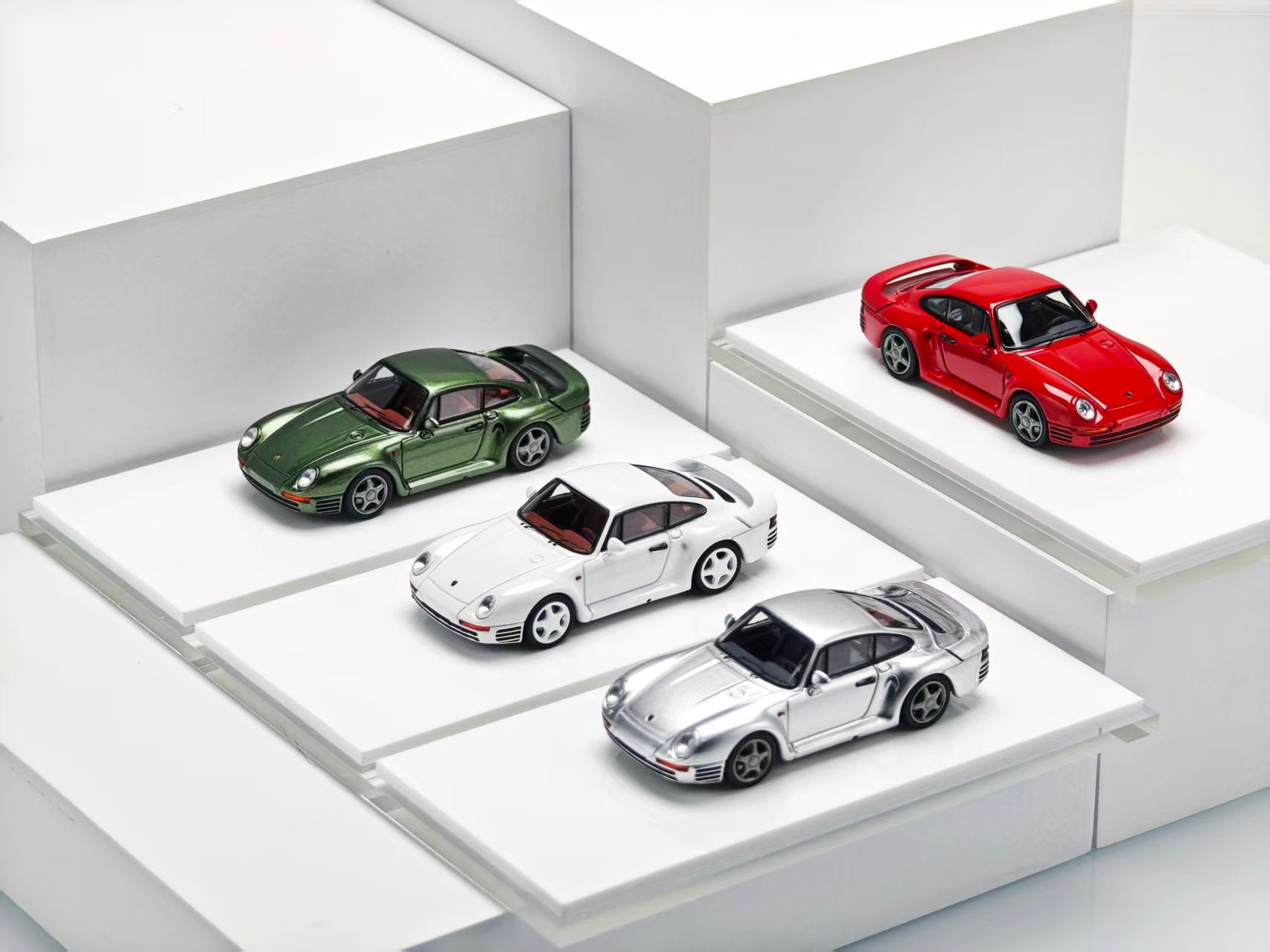 Four model cars displayed on a white platform with a white background