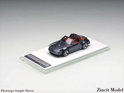 A miniature model of a dark gray convertible Porsche 911, displayed on a clear acrylic stand with a label, against a neutral gray background.