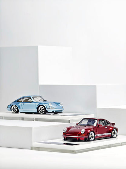 Two model cars on display stands against a white background