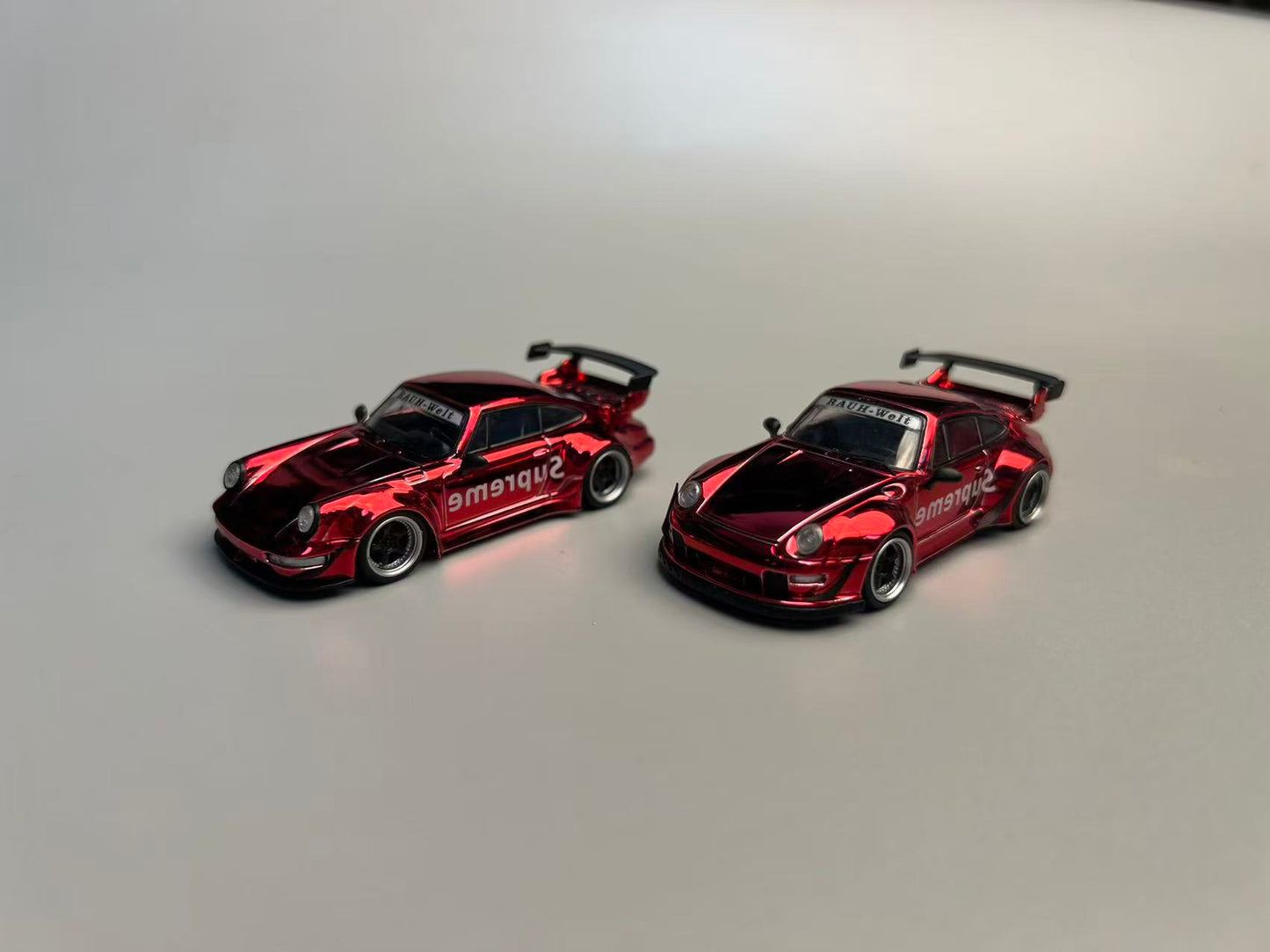 Two red model cars on a gray background