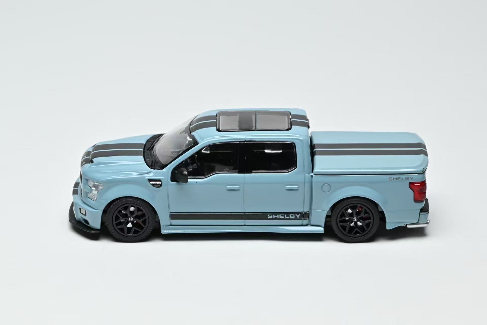 Light blue toy truck with black stripes on a white background