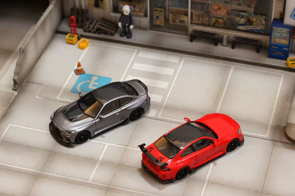 Two toy cars, one red and one black, on a tiled floor with a miniature store in the background.